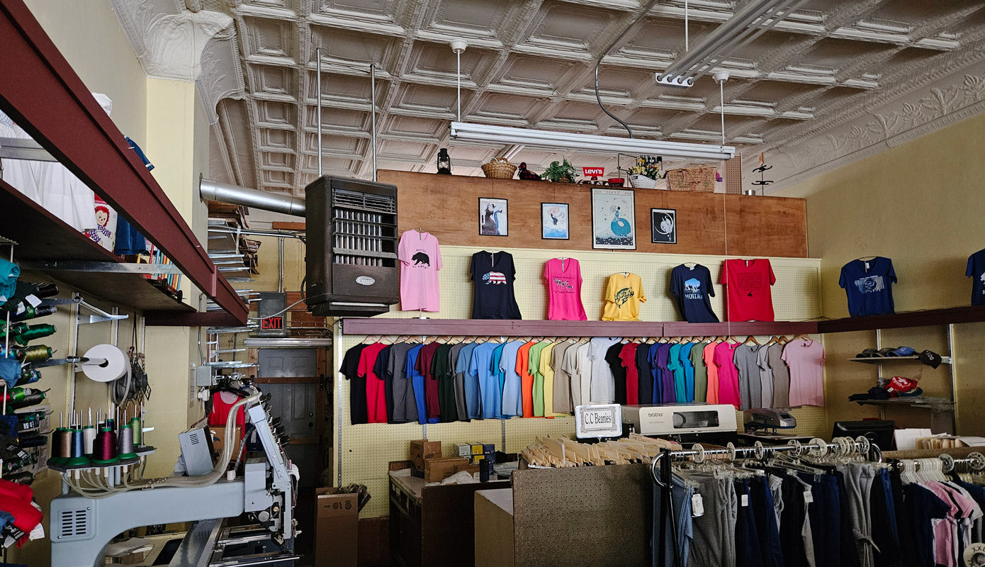embroidery machine with spools of thread, DTG printing machine, and t-shirts on display with vintage ceiling tiles above